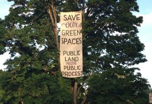 Save our green spaces banner hangs in a tree in potters field